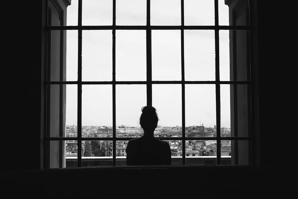 Silhouette di una persona alla finestra che osserva la città, in bianco e nero